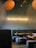 A cozy interior of a restaurant with gray upholstered seating and wooden tables. The wall displays a neon sign that reads 'RAMEN POWER,' creating a warm atmosphere. Overhead lighting adds to the soft, inviting ambiance.