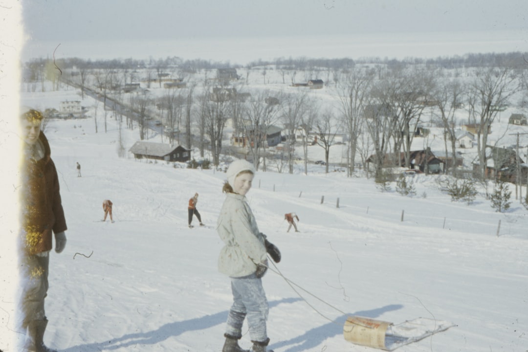 girl standing beside man on snow field