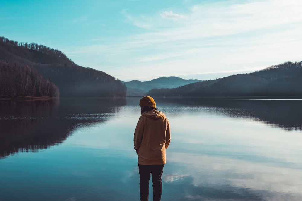 woman wearing brown hoodie on body of water