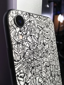 Close-up of a quirky mobile cover featuring playful doodles in bright yellow and white on a clean background.