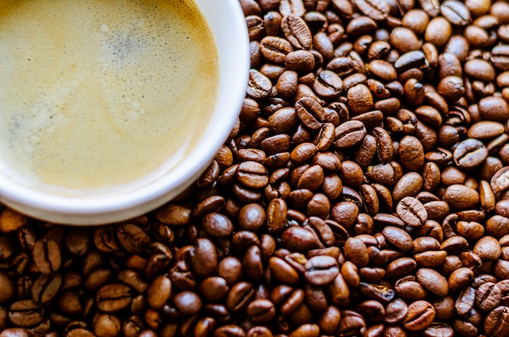 white ceramic mug on coffee beans