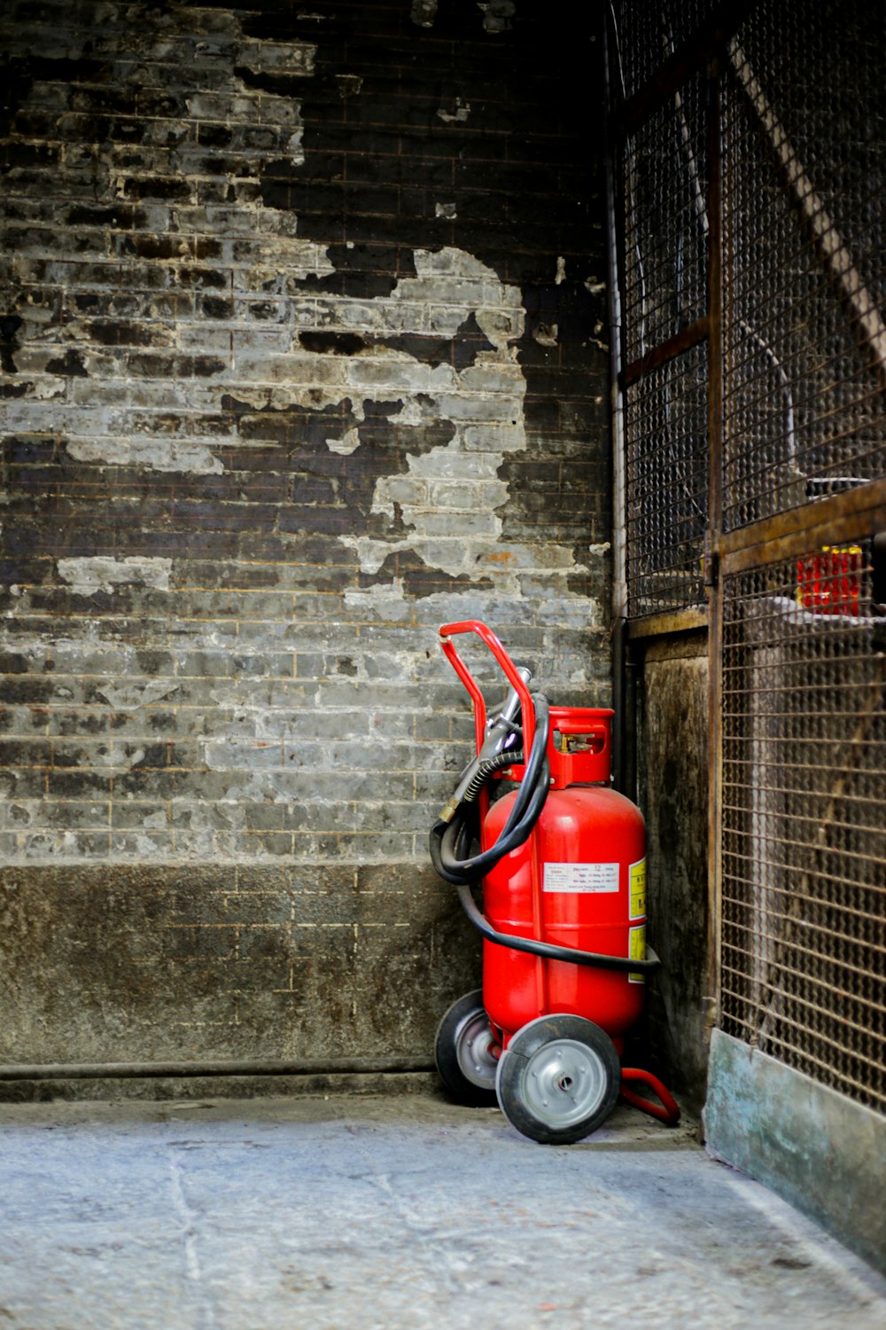 red propane tank on hand truck beside wall