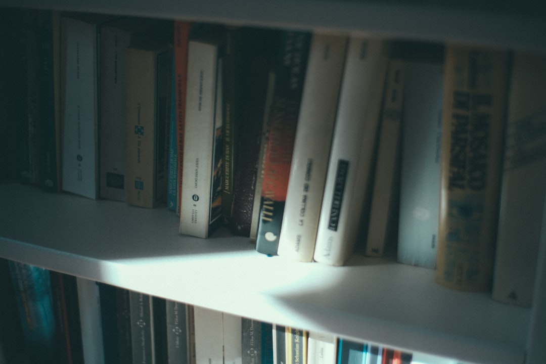 low-light photo of books on white shelves