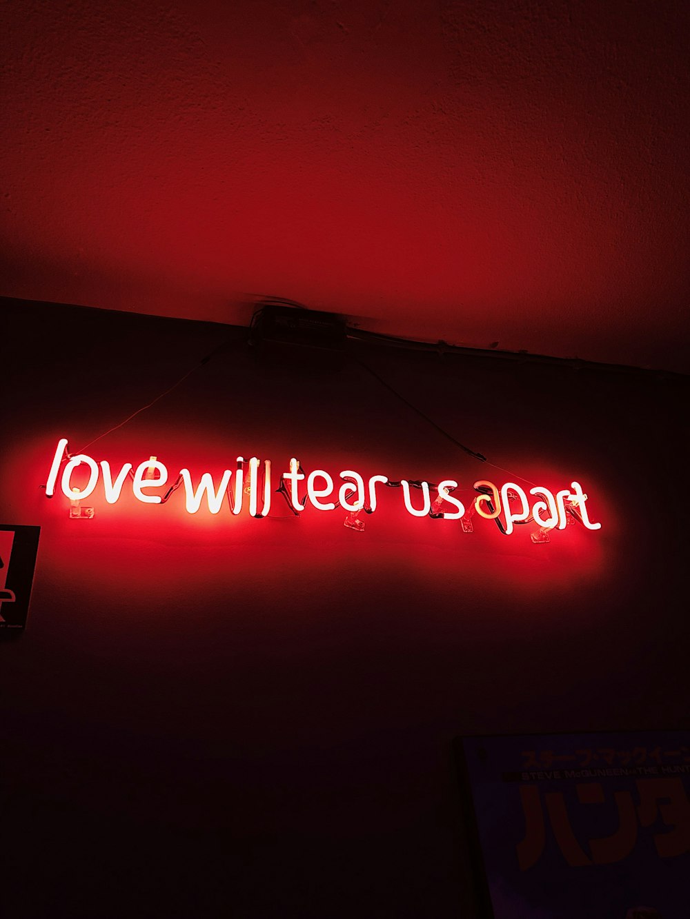 a neon sign that says love will tear us apart
