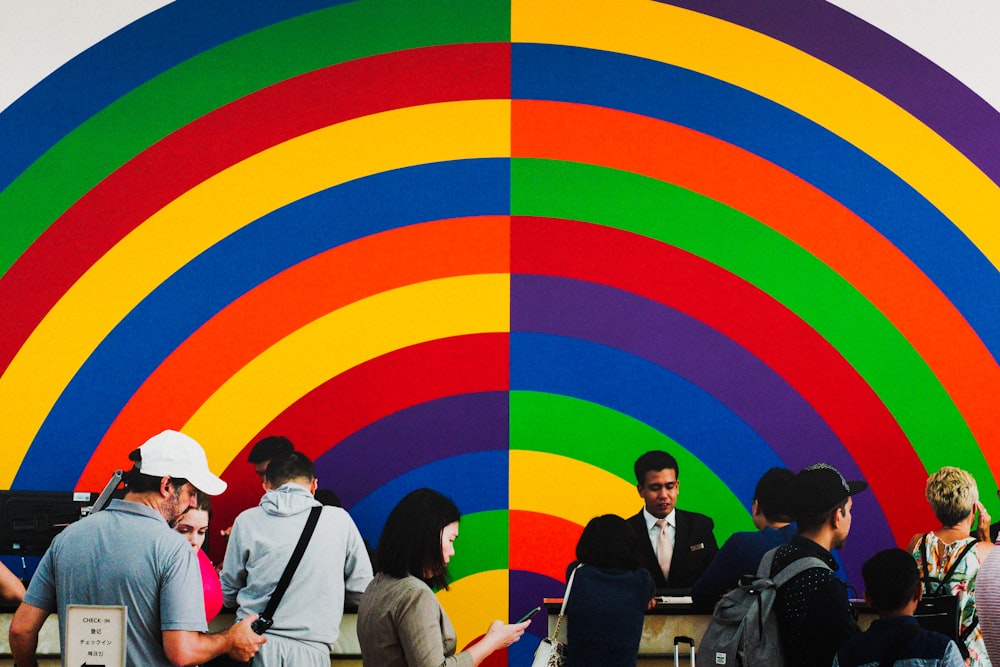 people standing beside multicolored wall