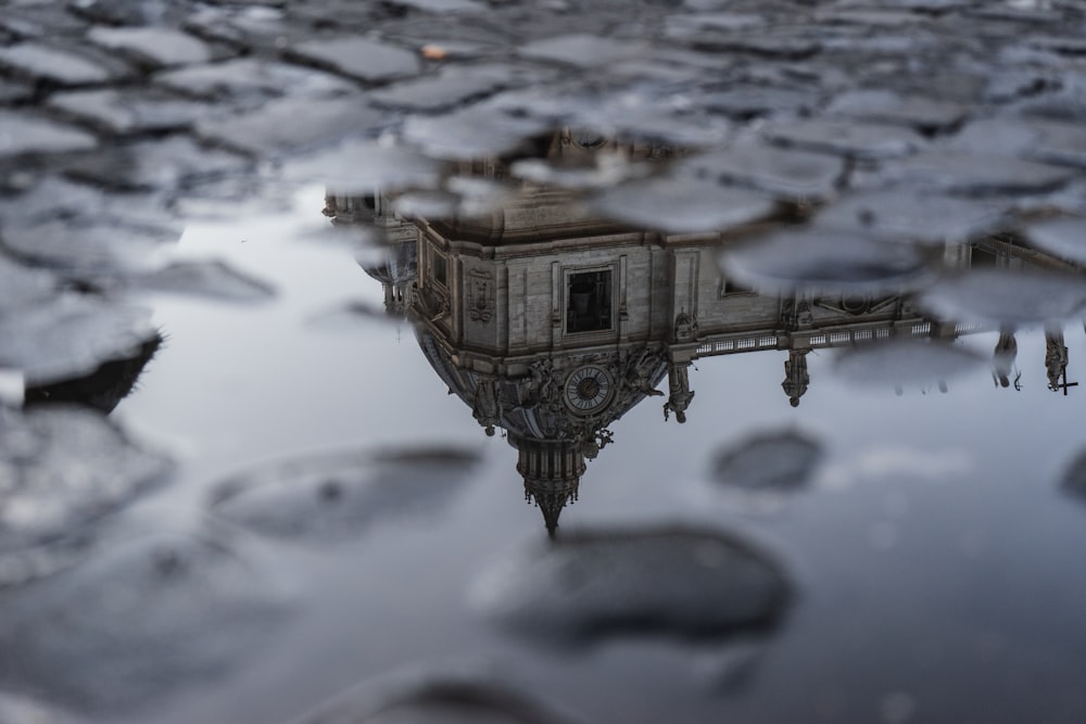 fotografia do edifício marrom refletindo no corpo de água