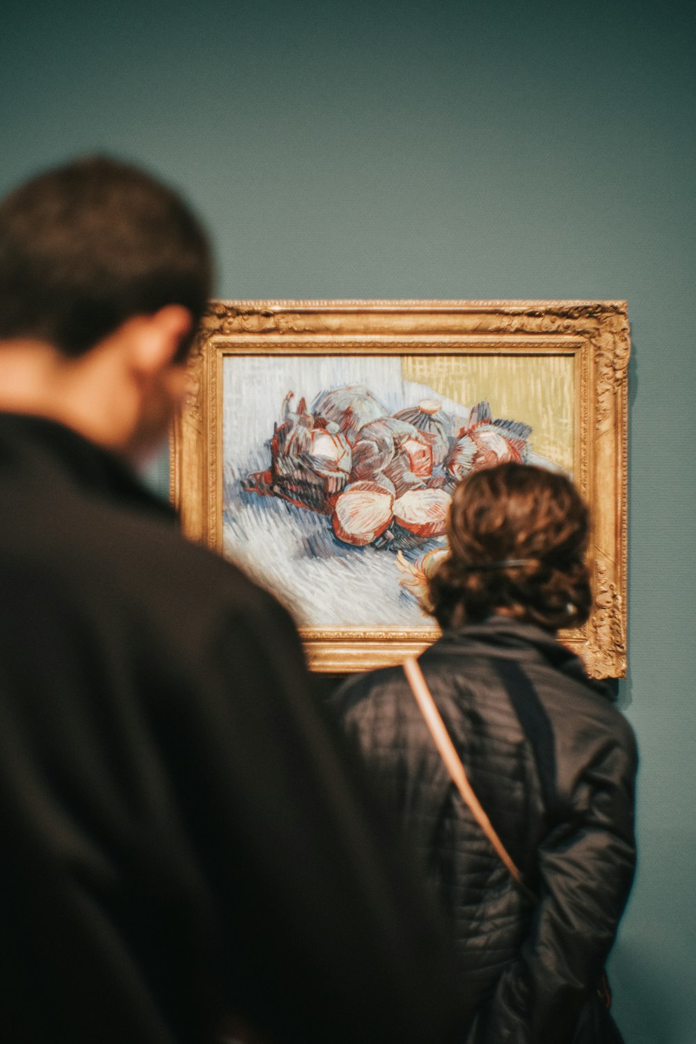 two people standing while watching Still Life With Red Cabbages And Onions painting by Vincent Van Gogh