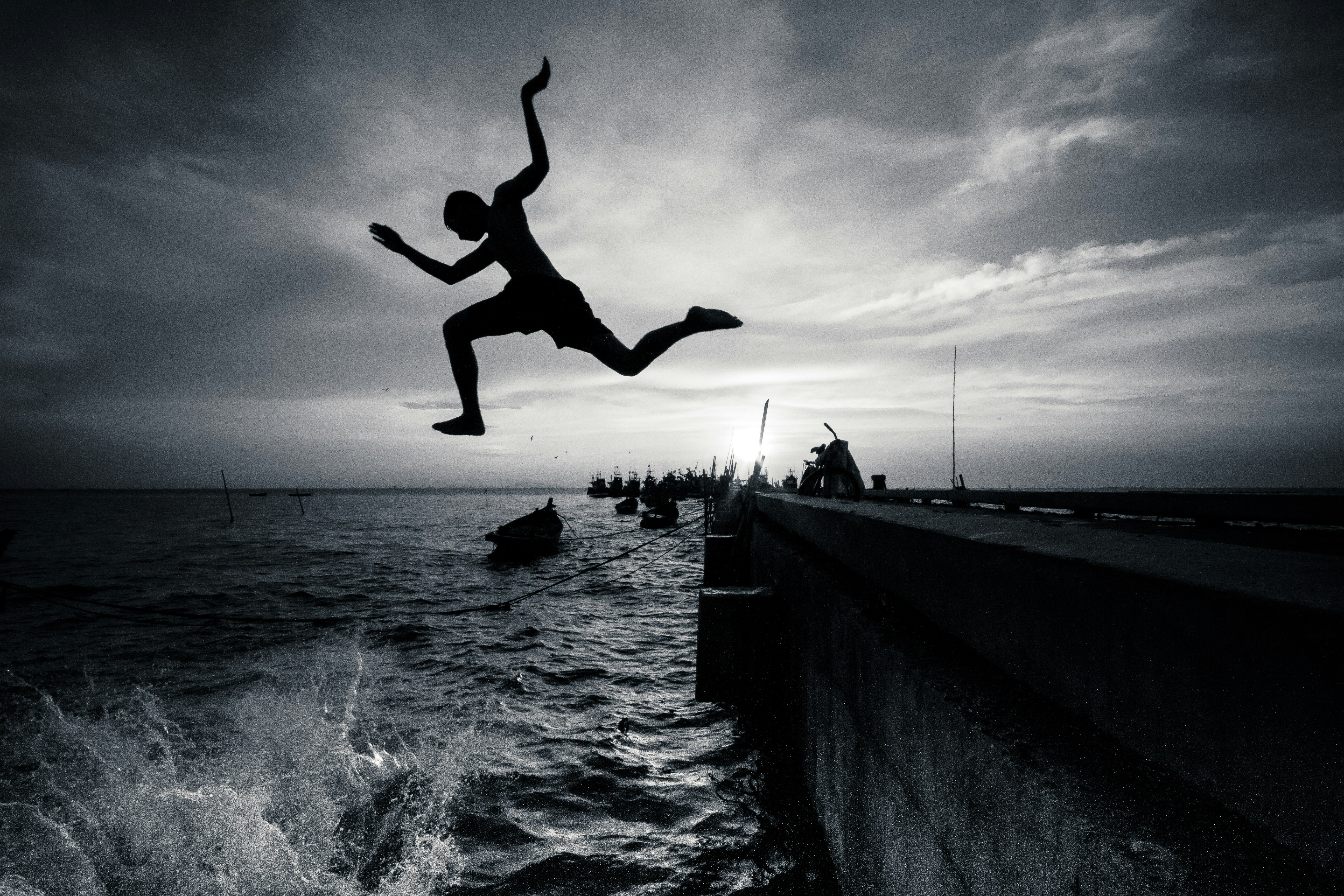 海でジャンプする男のシルエット写真の写真 Unsplashで見つけるグレーの無料写真