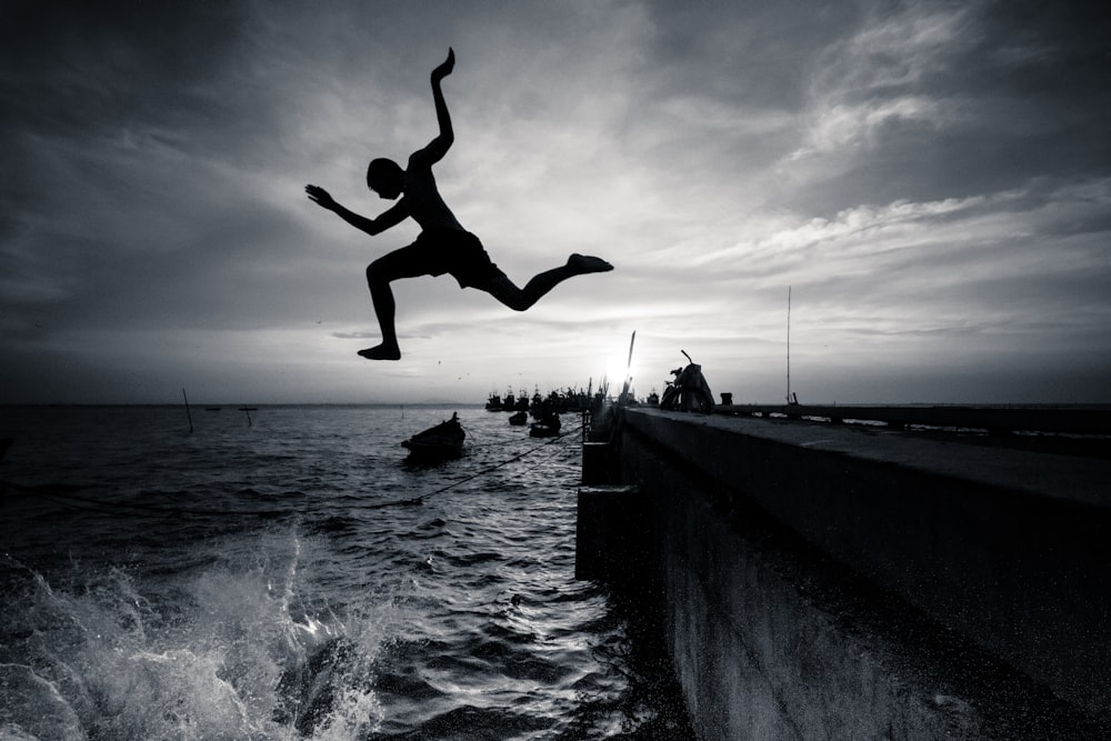 Silhouettenfotografie eines Mannes, der auf dem Meer springt