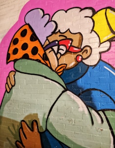 A vibrant graffiti artwork depicting two cartoonish characters embracing. One character has white curly hair, oversized red glasses, and wears a blue outfit, while the other is adorned with a spotted orange hat and green coat. The background is a bold pink color, adding to the lively and colorful nature of the artwork.
