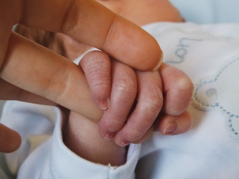 a close up of a person holding a baby's hand