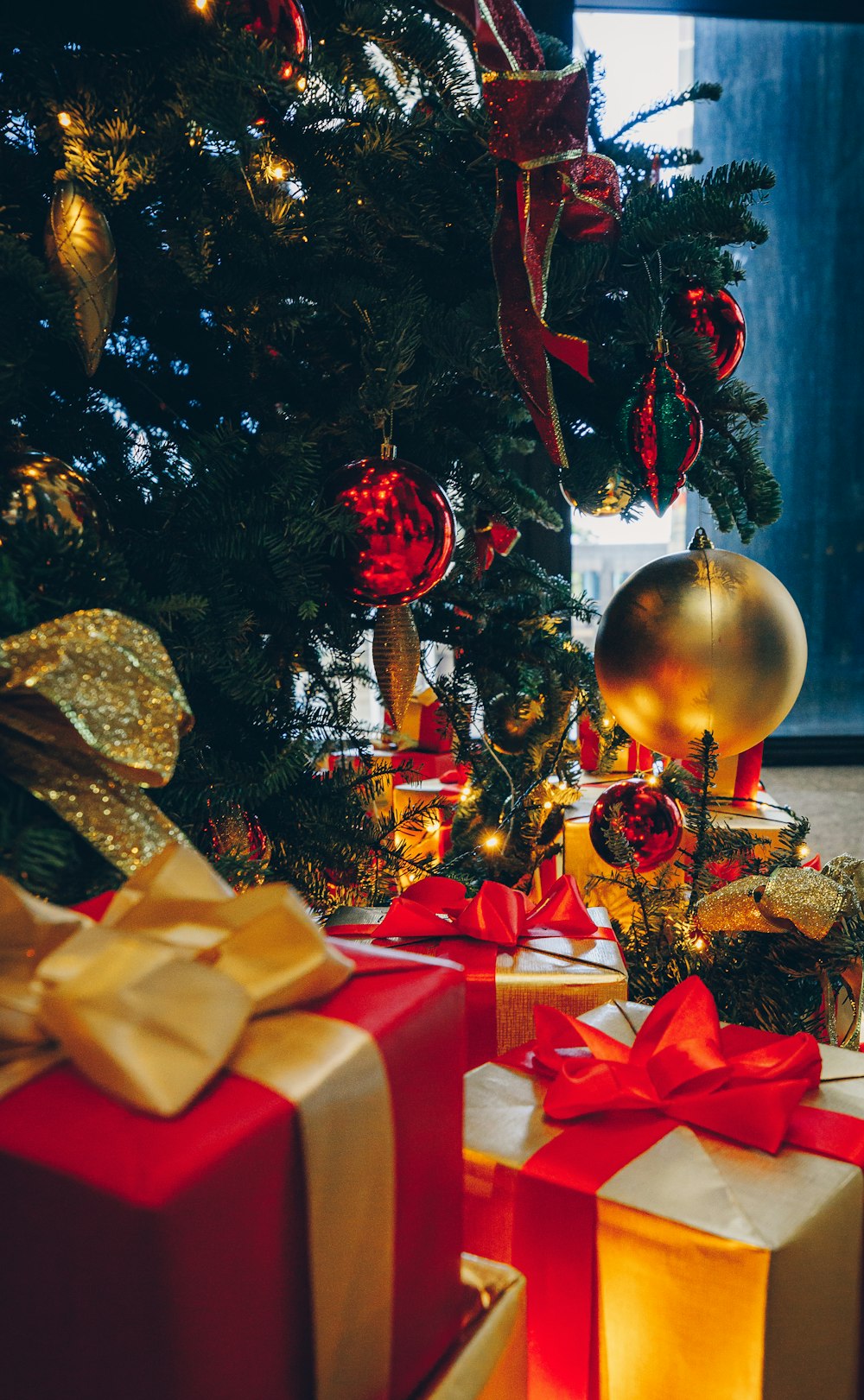 árvore de Natal verde com decorações e caixas de presente no chão