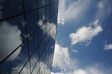 Large glass facade on a commercial building reflecting the blue sky.