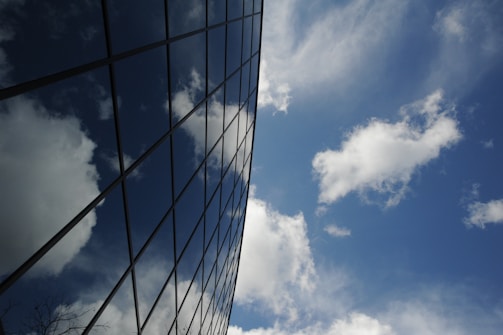Large glass facade on a commercial building reflecting the blue sky.