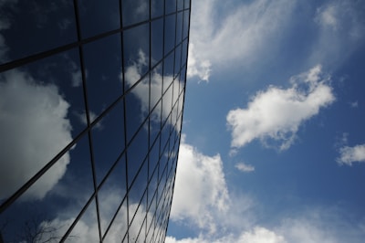 Large glass facade on a commercial building reflecting the blue sky.