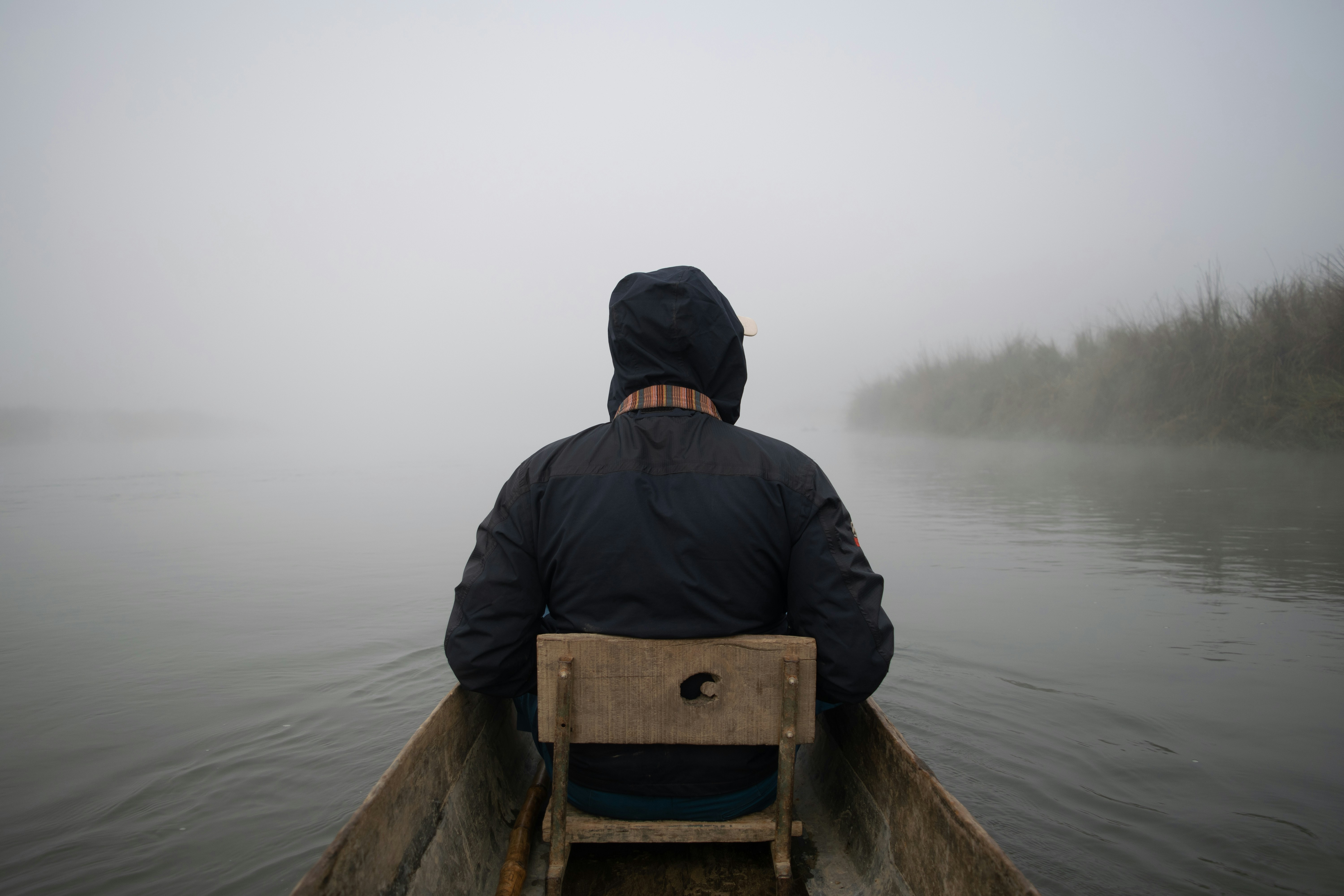 Man sailing a canoe through a foggy river