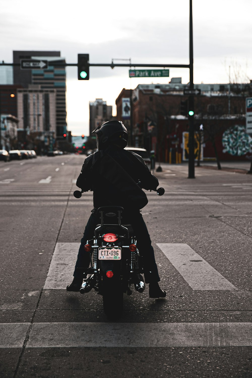 man riding motorcycle on crosswalk facing the traffic light displaying green light