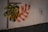 A wall features a colorful mural with abstract plant-like shapes intermingled, painted in vibrant hues of green, yellow, blue, and red. Black dotted lines form a grid pattern on one side, adding a modern touch. The wall is textured at the bottom, with some visible peeling on the side.