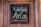 A chalkboard sign is framed in dark wood and fastened to a wooden surface. The chalkboard displays the message 'We have AirCon' written in white and yellow chalk in a casual, handwritten style.