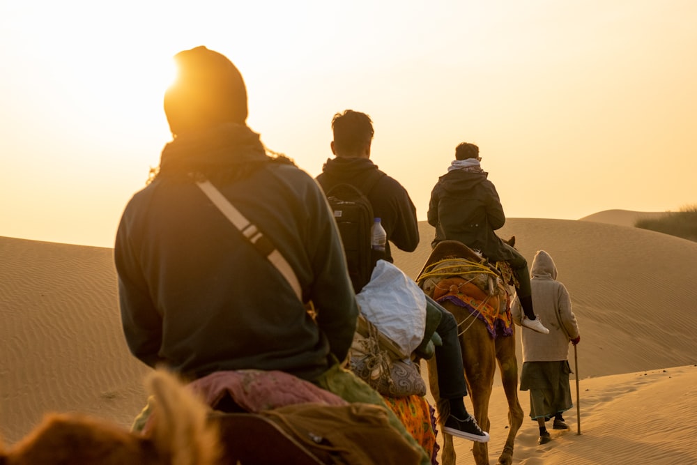 three men riding on camels