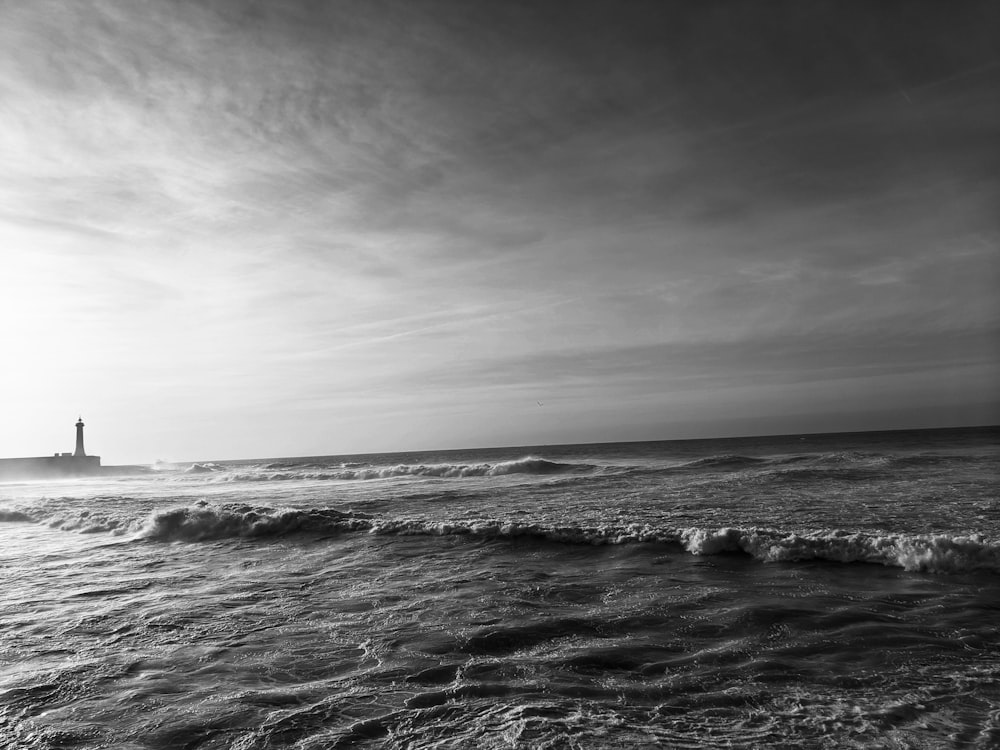 grayscale photography of lighthouse near body of water