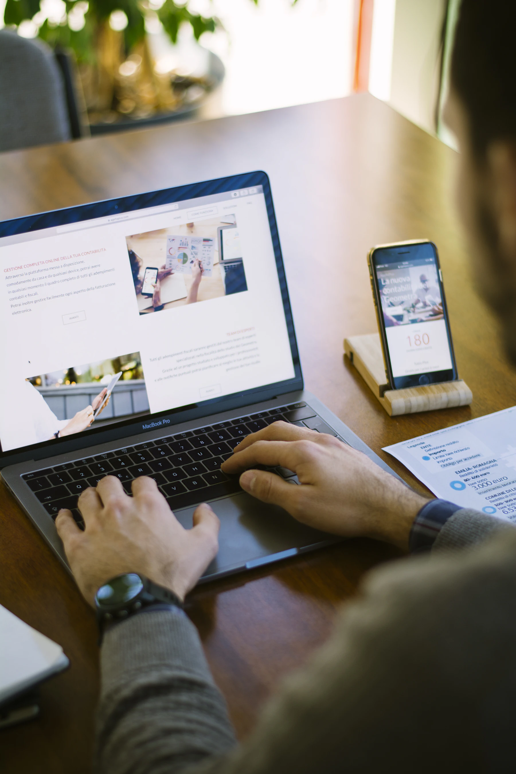Homeoffice-Arbeitsplatz mit Laptop, Smartphone und Unterlagen auf einem Holztisch