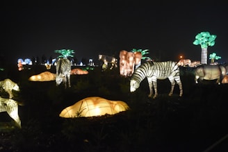 The Night Safari’s lush greenery illuminated by soft lighting, with a glimpse of nocturnal animals.