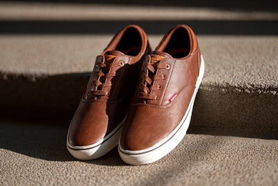 A pair of classic leather sneakers resting on a concrete floor with soft shadows.