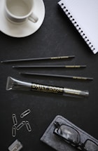 A stylish desk with eyeglasses, a notebook, and a laptop ready for a creative meeting.