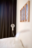 A minimalist bedroom featuring a delicate string of fairy lights draped above a calm, neutral-toned bed.