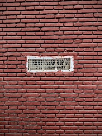 A sleek metal sign with bold lettering mounted on a brick wall.