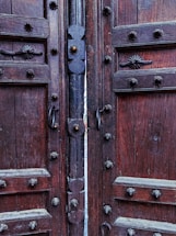 A warm, inviting wooden door slightly ajar, showcasing fine craftsmanship and natural wood grain.