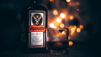 green Jagermeister liquor bottle beside rock glass