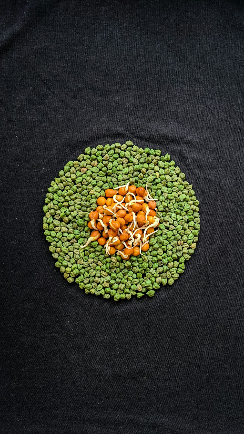 a plate of peas, carrots and sprouts on a black surface