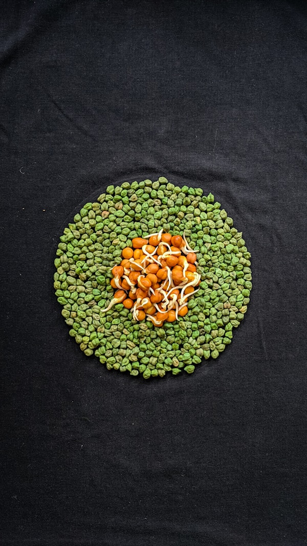 A plate of peas, carrots and sprouts on a black surface