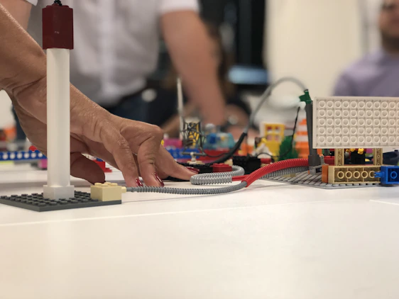 A close-up of hands assembling colorful building blocks on a wooden table, symbolizing website construction in progress.