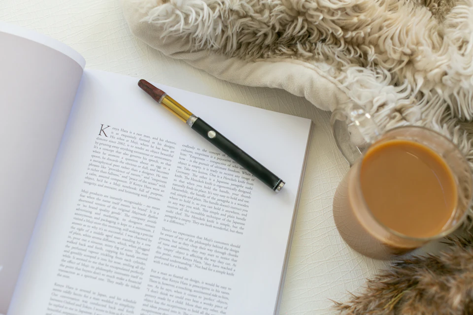 Open book with black pen resting on top against white background