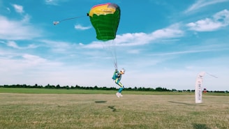 The balloon landing safely on a grassy field with the pilot guiding the descent.