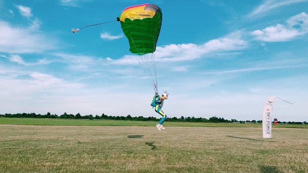 The balloon landing safely on a grassy field with the pilot guiding the descent.