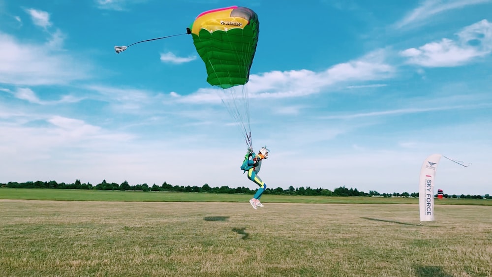 parachuting person landing on green grass