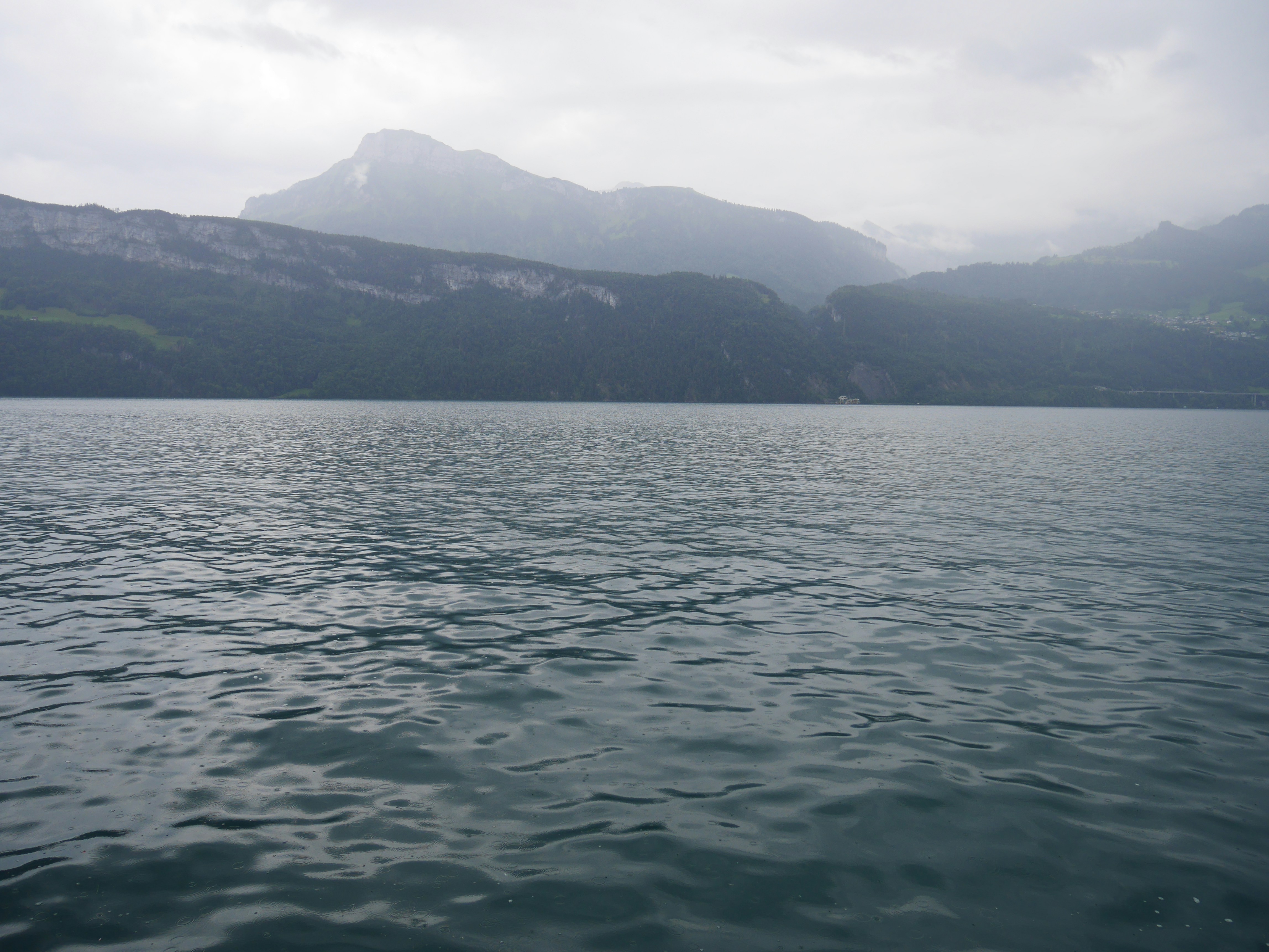 A calm lake at dawn with gentle ripples under a pale sky.