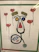 A creative artwork features elements resembling a face made from various objects, including a stethoscope forming the outline, yarn or string for the eyebrows, and colorful circular objects for the eyes. Surrounding the face are floating heart-shaped balloons with red color as the main theme.