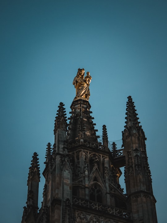 cathedral with statue on top during day in Bordeaux Cathedral France