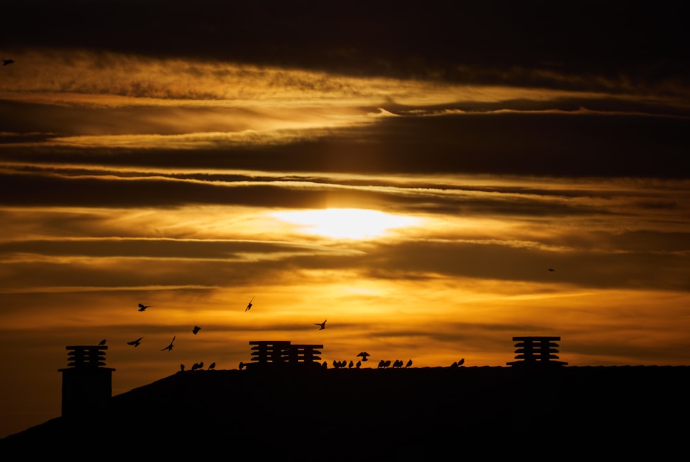 silhouette of buildings under cloudy sky during golden hour