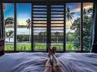 Luxurious villa bedroom with large windows overlooking tropical gardens.