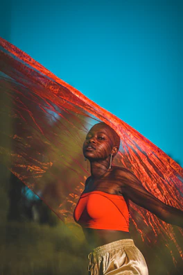 Model walking confidently in a flowing dress with a sunset orange backdrop.