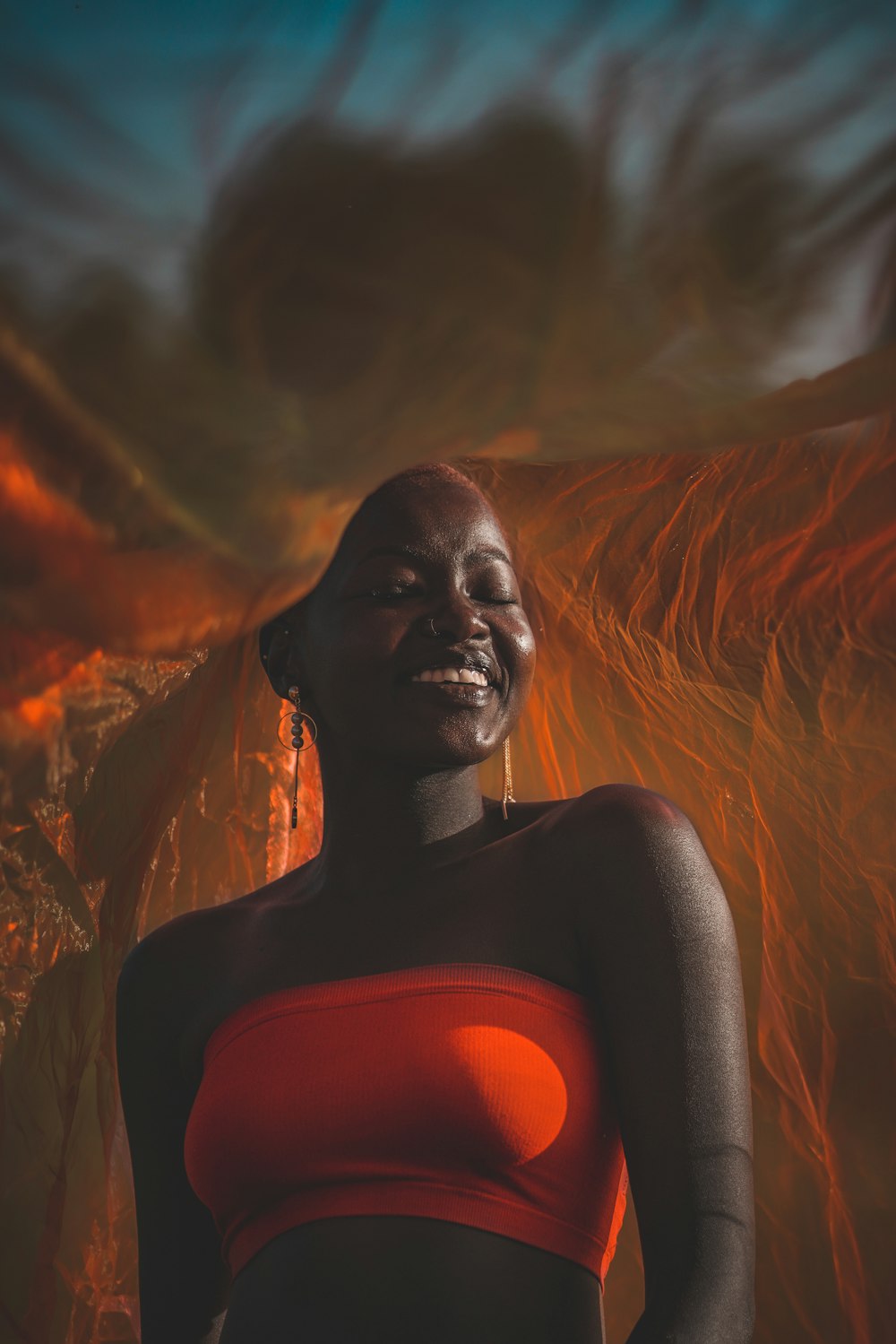 woman wearing orange tube under white sheet while smiling