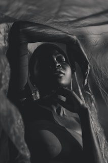 An intimate studio shot featuring a model draped in flowing fabric, with dramatic shadows.