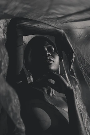 Cinematic portrait of an elite individual draped in futuristic tribal leather fashion, set in shadowed ambiance.