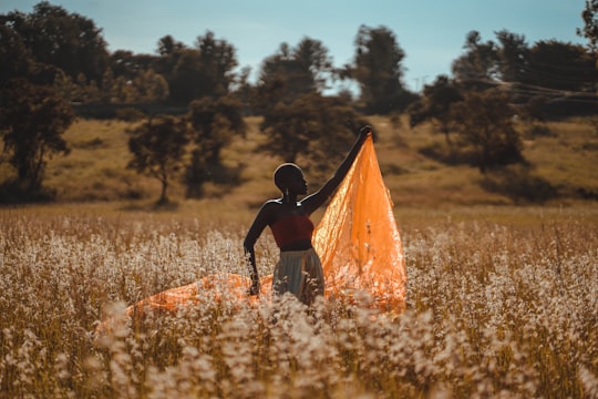 woman standing and holding orange textile at the field during day in Nairobi Kenya